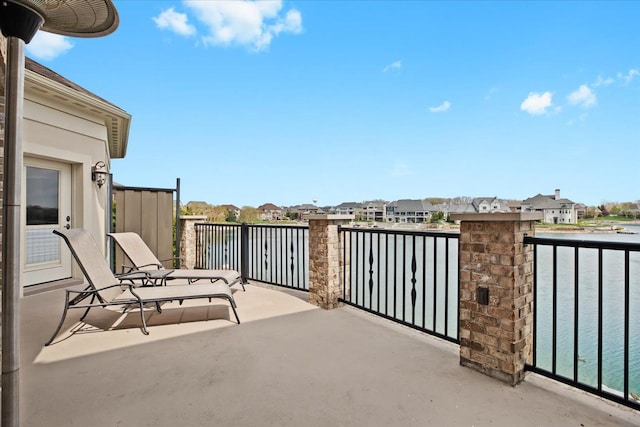 view of patio featuring a water view, a residential view, and a balcony