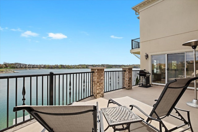 exterior space with grilling area, a water view, and a balcony