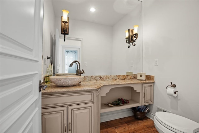 bathroom with toilet, wood finished floors, vanity, visible vents, and baseboards