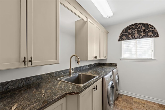 laundry area featuring a sink, cabinet space, stone finish floor, separate washer and dryer, and baseboards