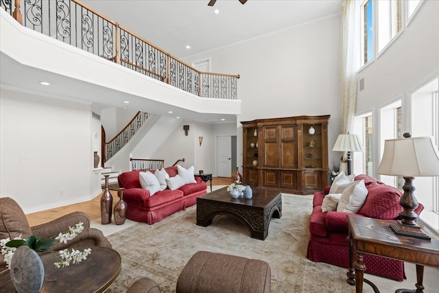 living area with stairs, plenty of natural light, recessed lighting, and a towering ceiling