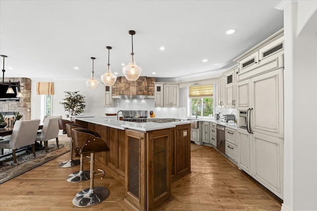 kitchen with recessed lighting, glass insert cabinets, a kitchen bar, decorative backsplash, and light countertops
