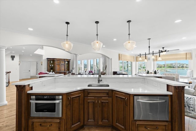 kitchen with light wood-style flooring, a sink, oven, decorative columns, and open floor plan