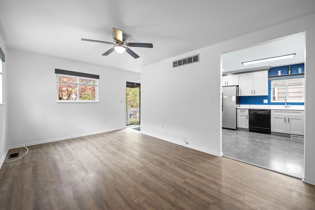 unfurnished living room featuring visible vents, a ceiling fan, wood finished floors, baseboards, and a sink