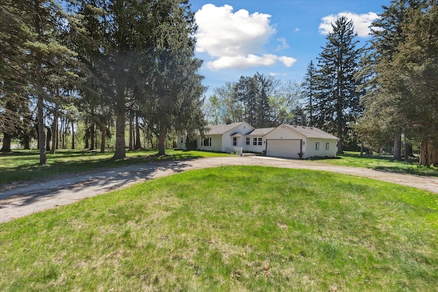 ranch-style home featuring curved driveway, an attached garage, and a front yard