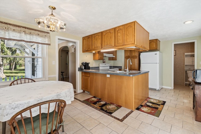 kitchen with arched walkways, range with electric cooktop, freestanding refrigerator, a peninsula, and under cabinet range hood