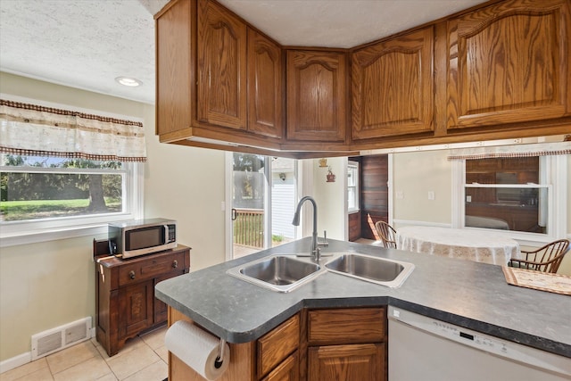 kitchen featuring visible vents, white dishwasher, a sink, light tile patterned floors, and stainless steel microwave