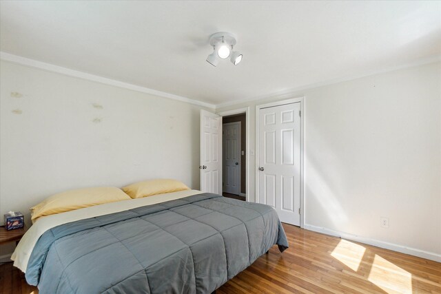 bedroom featuring crown molding, baseboards, and wood finished floors
