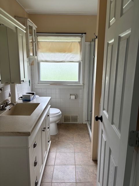 full bathroom with visible vents, vanity, toilet, tile patterned floors, and a shower stall