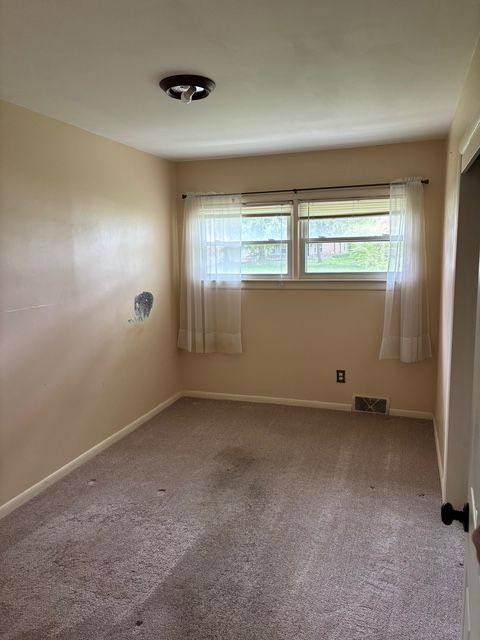 unfurnished room with visible vents, baseboards, and carpet floors