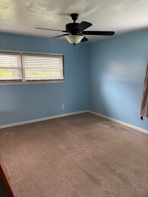 spare room featuring carpet floors, ceiling fan, and baseboards