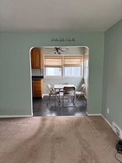 dining room featuring arched walkways, ceiling fan, dark colored carpet, and visible vents