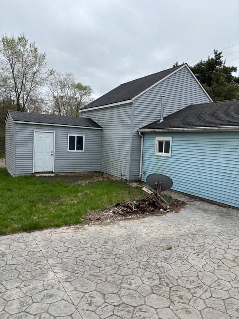 rear view of house featuring a storage unit, a patio, an outbuilding, and a yard