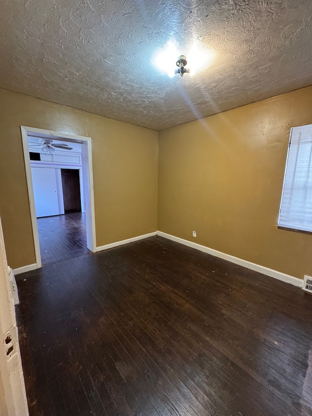 unfurnished room with ceiling fan, a textured ceiling, visible vents, hardwood / wood-style flooring, and baseboards
