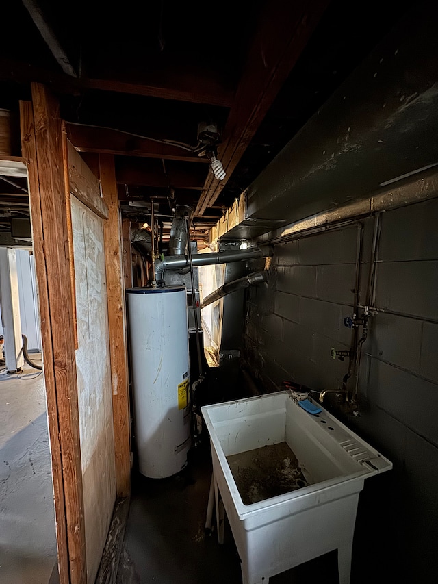 below grade area with a sink, concrete block wall, and gas water heater