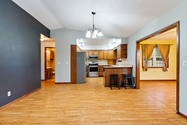 kitchen with lofted ceiling, stainless steel appliances, brown cabinets, and light wood-style floors