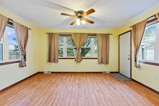 empty room with ceiling fan, baseboards, visible vents, and light wood-style floors