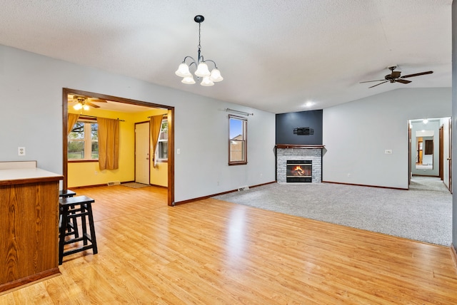 unfurnished living room with baseboards, a healthy amount of sunlight, and ceiling fan with notable chandelier