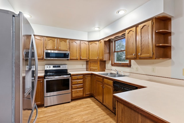 kitchen with a sink, brown cabinetry, light wood-style flooring, and appliances with stainless steel finishes