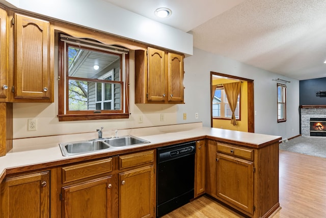 kitchen featuring light countertops, a peninsula, a sink, and dishwasher