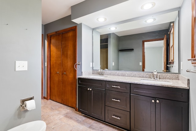 full bath with a sink, double vanity, and toilet