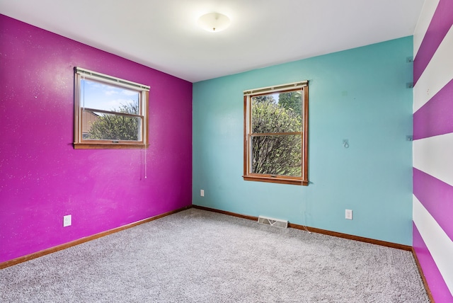 carpeted empty room featuring visible vents and baseboards