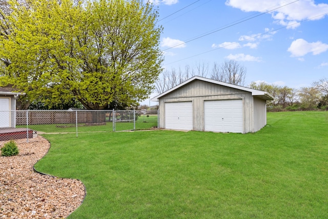 view of yard featuring fence, a detached garage, and an outdoor structure