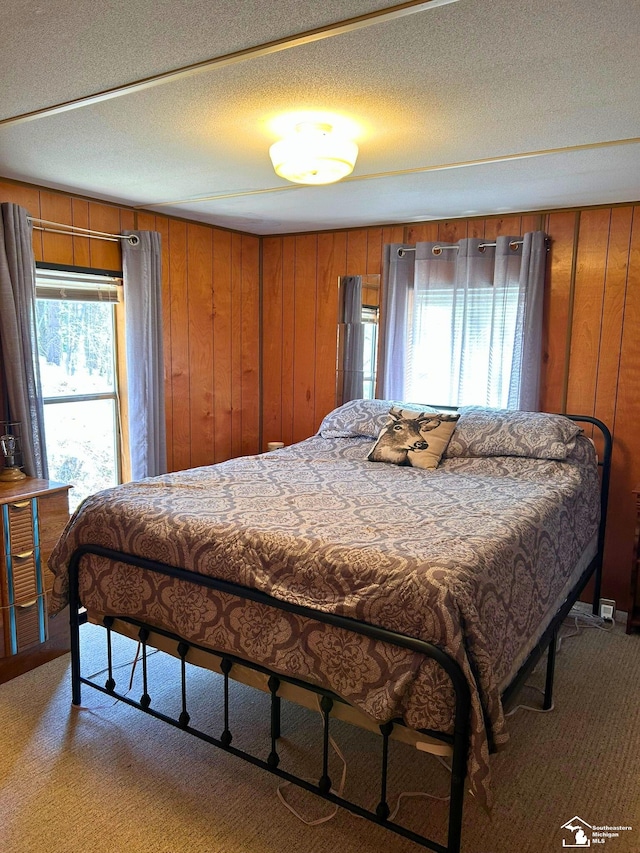 carpeted bedroom featuring wooden walls and a textured ceiling