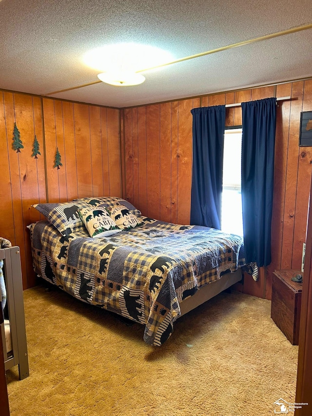 bedroom featuring light colored carpet, a textured ceiling, and wooden walls