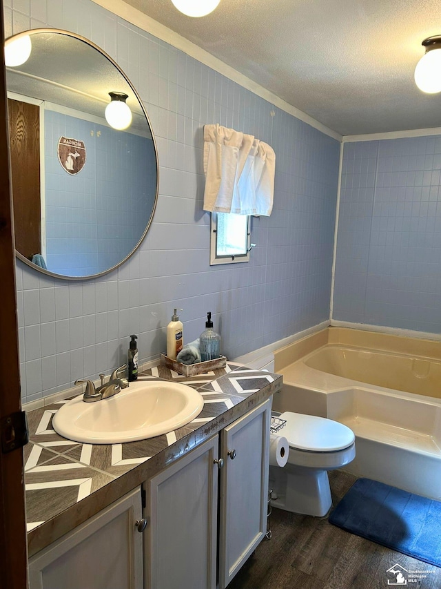 bathroom with crown molding, vanity, toilet, wood finished floors, and a bath