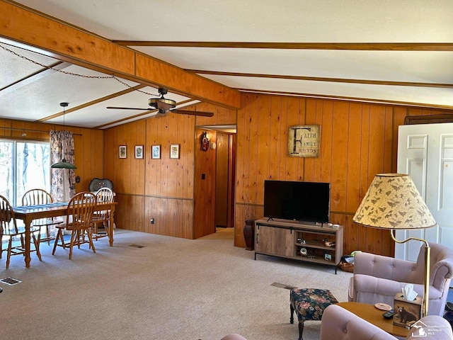 living area with wooden walls, ceiling fan, and beam ceiling