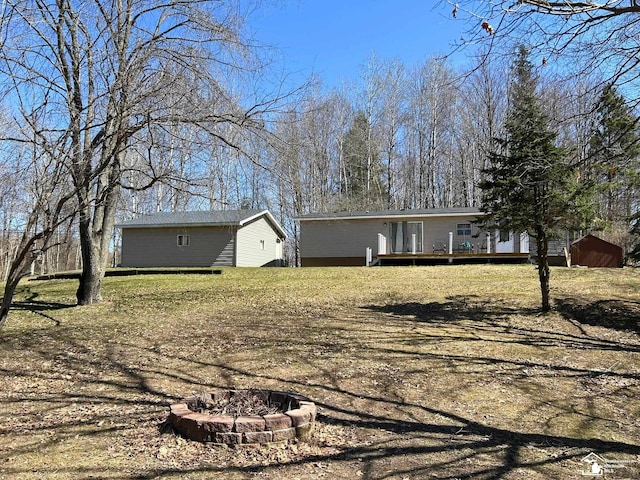 view of yard featuring a storage unit, an outdoor structure, an outdoor fire pit, and a deck