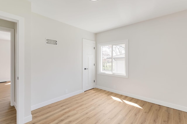spare room featuring baseboards, wood finished floors, and visible vents