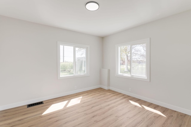 empty room featuring baseboards, light wood finished floors, and visible vents