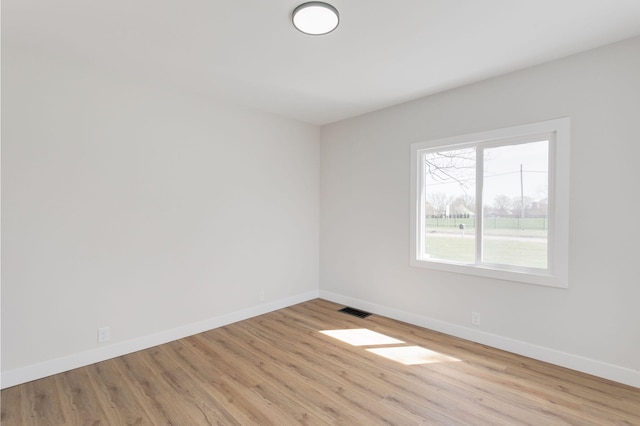 unfurnished room with baseboards, wood finished floors, and visible vents