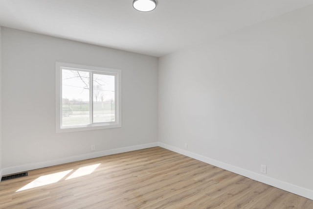 spare room featuring baseboards, visible vents, and light wood-type flooring