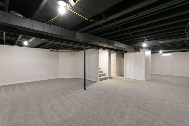 below grade area featuring carpet floors, baseboards, and stairway