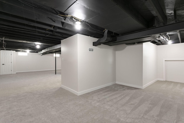 finished below grade area featuring baseboards, carpet, and visible vents