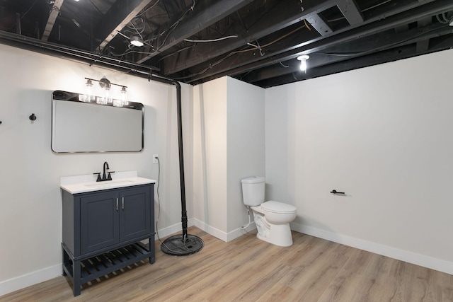 bathroom with toilet, baseboards, wood finished floors, and vanity