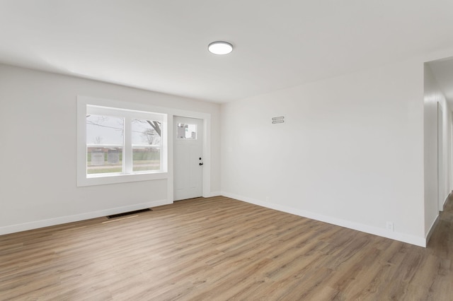 foyer with baseboards, light wood finished floors, and visible vents