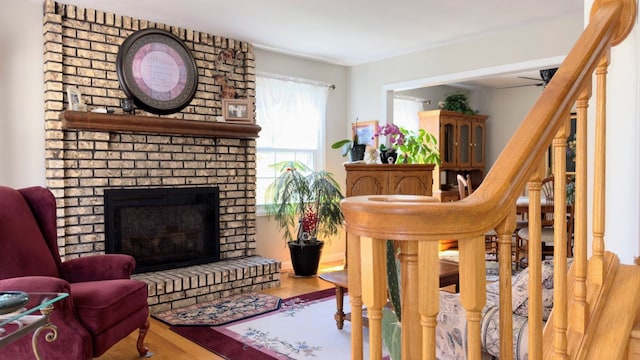 living area featuring ceiling fan, a fireplace, and wood finished floors