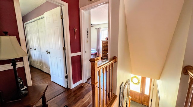 hall with baseboards, wood finished floors, and an upstairs landing