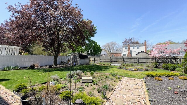 view of yard with a fenced backyard, a storage unit, an outdoor structure, and a vegetable garden