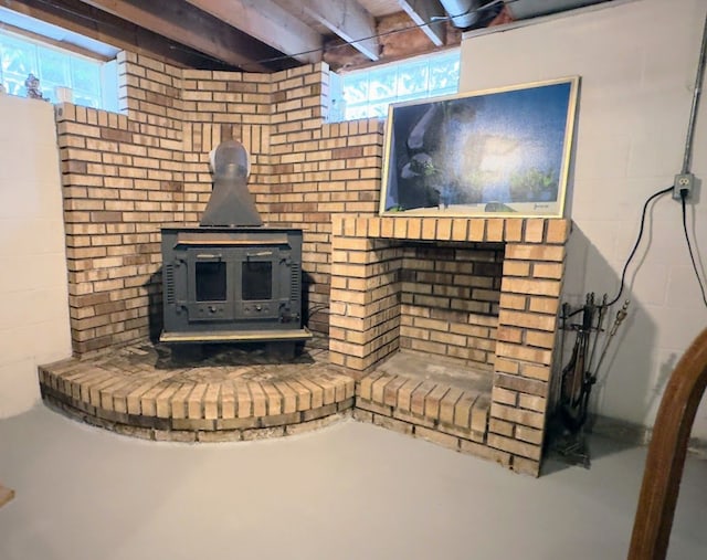 unfurnished living room featuring concrete flooring, concrete block wall, plenty of natural light, and a wood stove