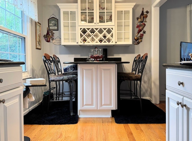 dining room with baseboards, a dry bar, and light wood-style flooring