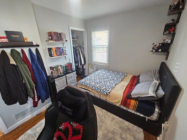 bedroom featuring visible vents, wood finished floors, baseboards, a closet, and a spacious closet