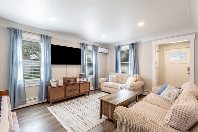 living room with baseboard heating, an AC wall unit, and wood finished floors