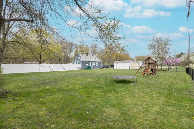 view of yard with an outdoor structure, a fenced backyard, a playground, a trampoline, and a storage shed