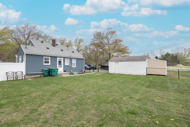 back of house featuring a yard, an outbuilding, a chimney, and a fenced backyard