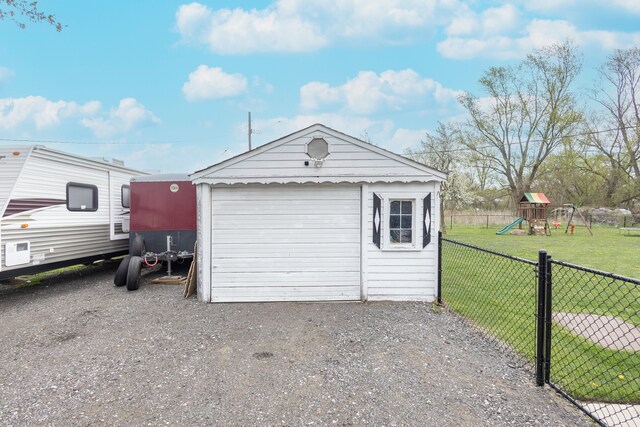 detached garage featuring fence and driveway